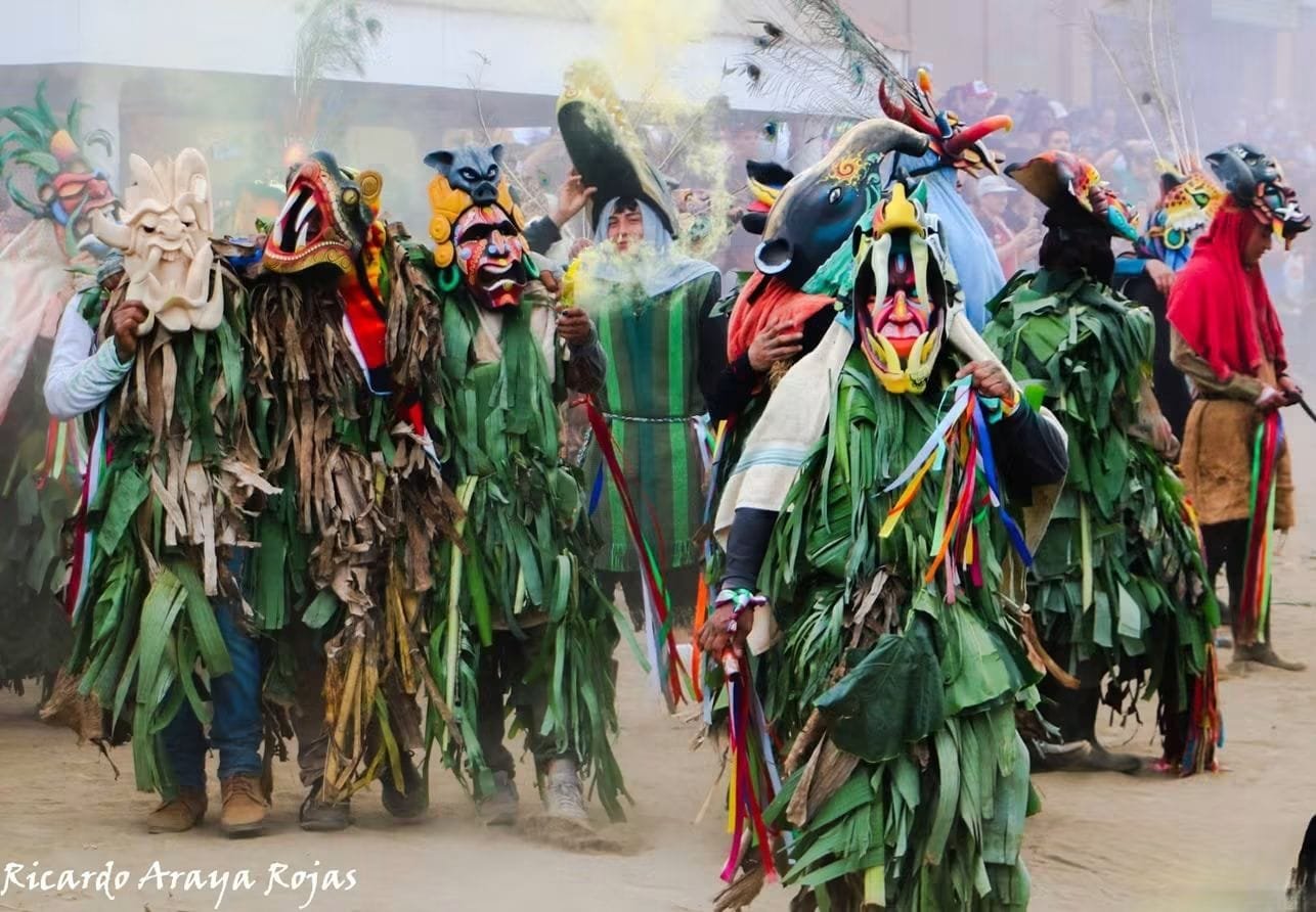 Guerreros cubiertos de hojas y con máscaras de colores avanzan entre humo amarillo