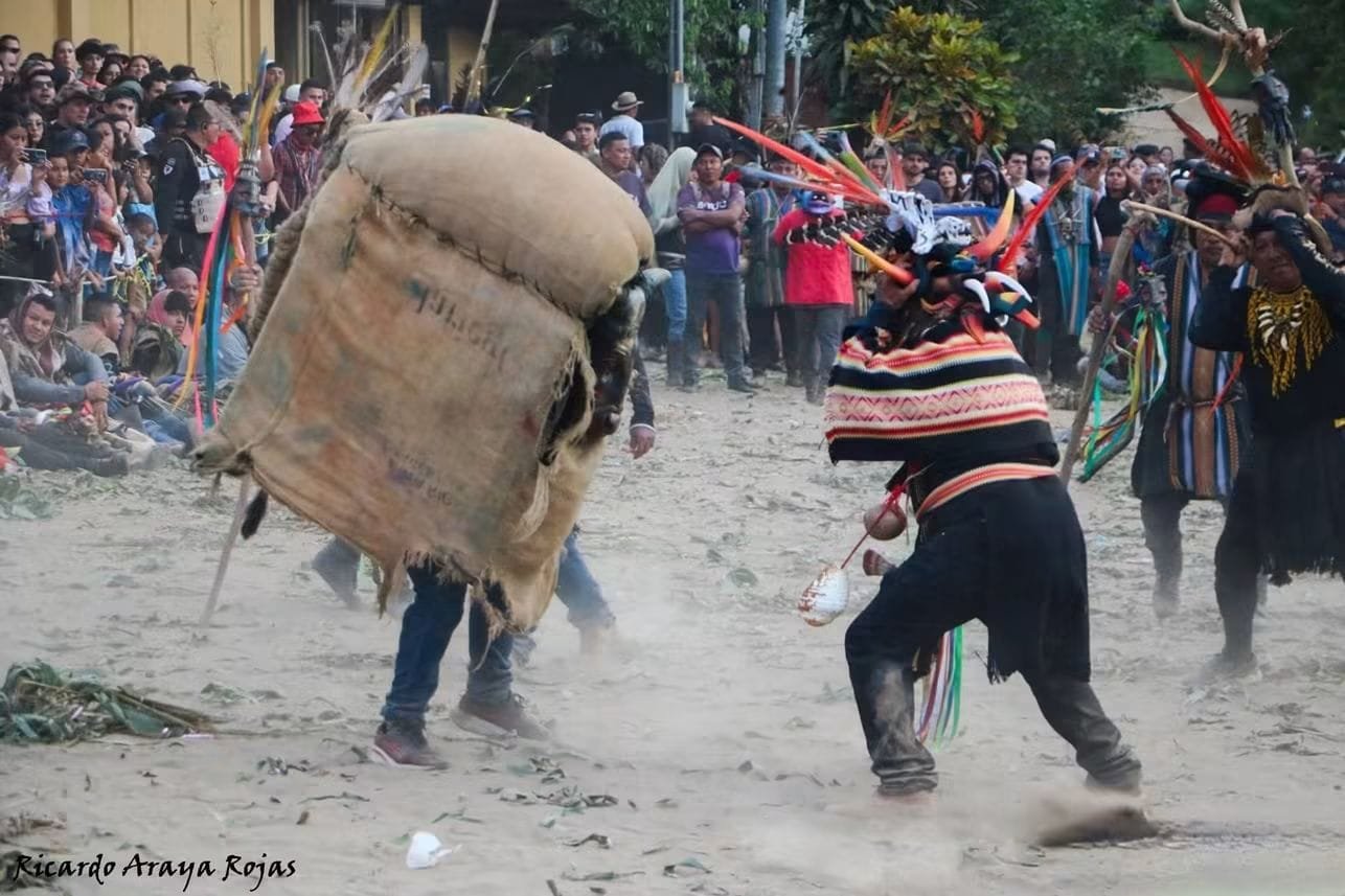 Un guerrero con tocado de plumas enfrenta al toro de tela de saco entre una nube de polvo